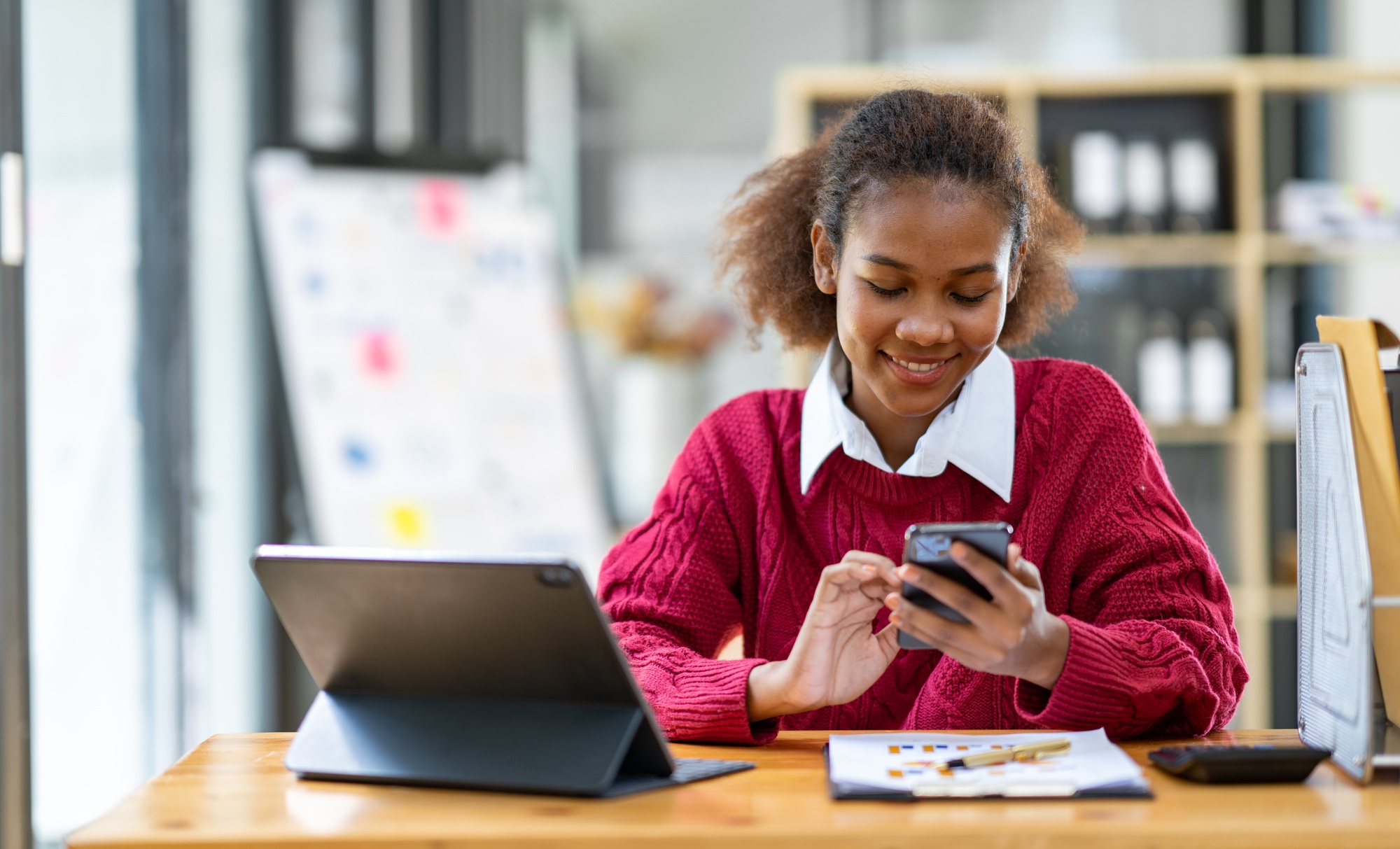 Portrait of an African businesswoman smiling cheerfully and talking on the phone with a colleague ab
